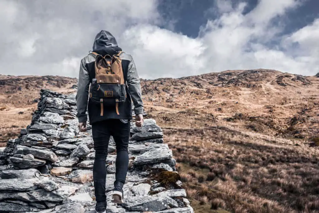 caminando por un sendero de piedra de montaña con una mochila